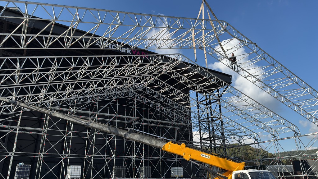 Large scale scaffolding structure being assembled by a crane during the day